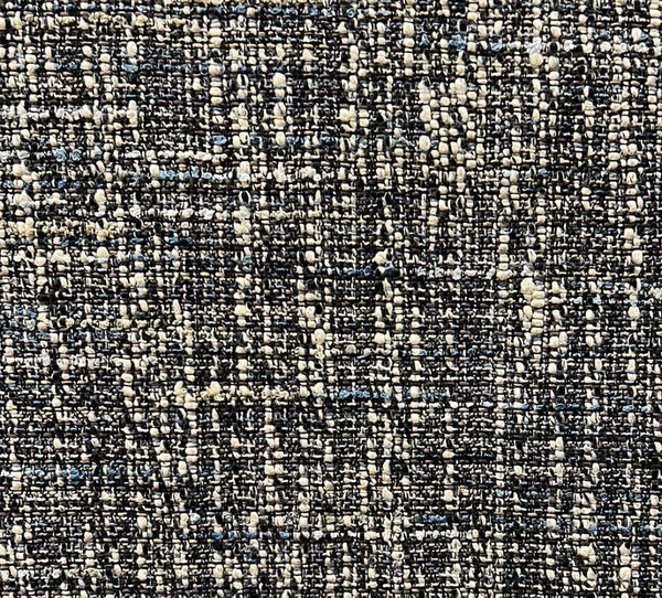 Close-up of a textured fabric with a tweed pattern featuring multiple colors including black, beige, and blue.