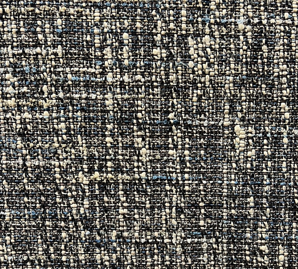 Close-up of a textured fabric with a tweed pattern featuring multiple colors including black, beige, and blue.