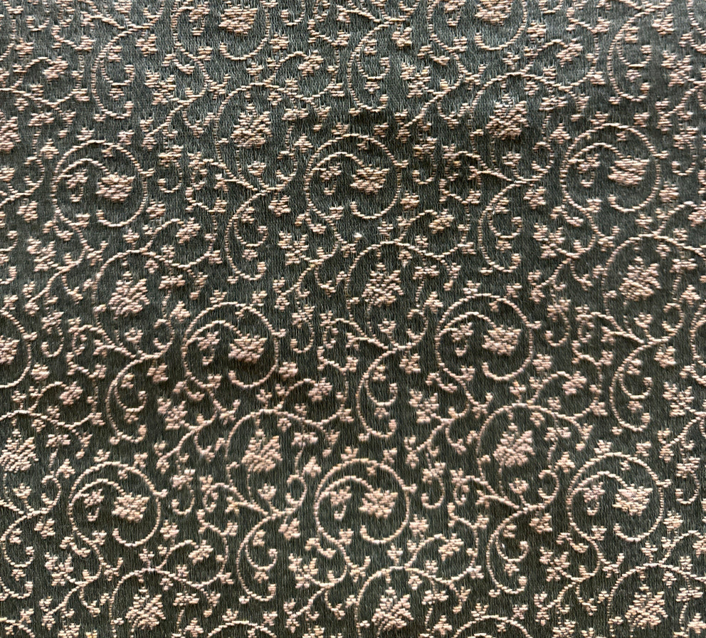 A close-up image of a patterned fabric with a floral design in a bronze color.