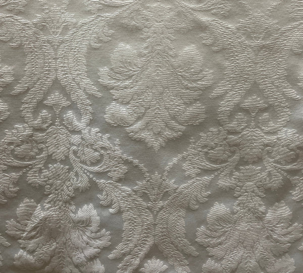 A close-up of a white fabric with a floral lace-like pattern.