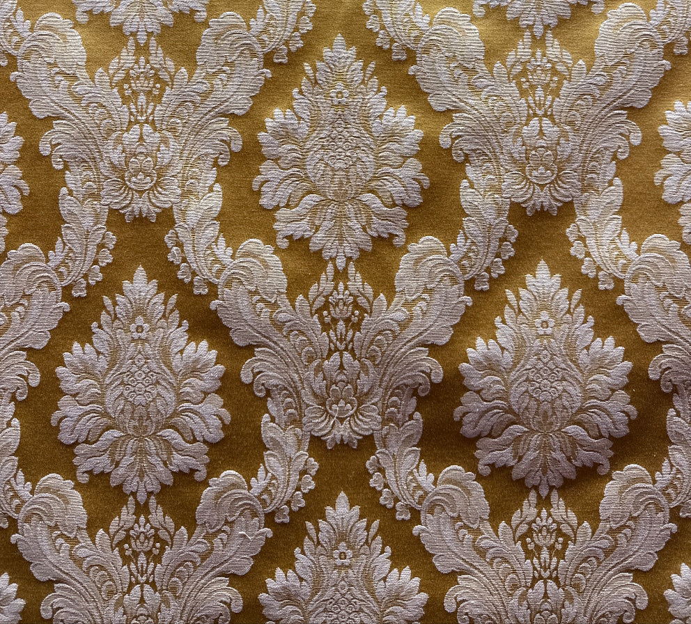 A close-up image of a golden yellow fabric with a white floral pattern.