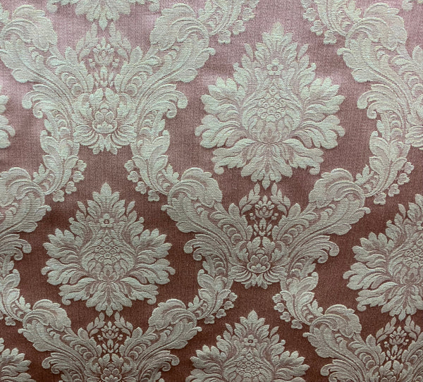 A piece of fabric with a floral damask pattern in a beige color on a brown background.
