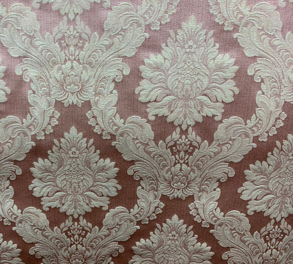 A piece of fabric with a floral damask pattern in a beige color on a brown background.
